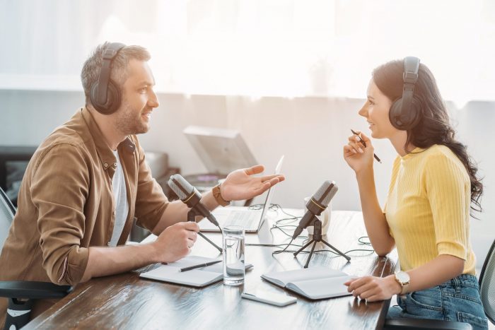 Two hosts in headphones talking while recording Airbnb podcasts