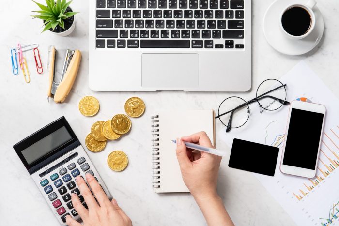 Woman calculating with a laptop, cell phones and a calculator 